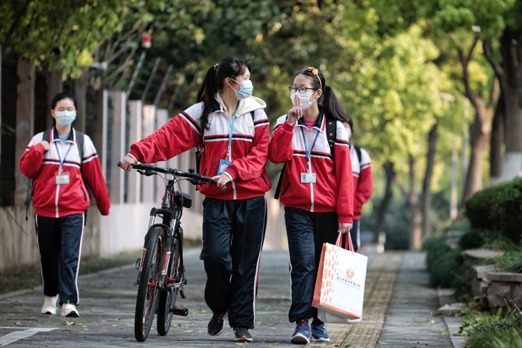 4月13日,学生们在上学路上有说有笑.学生进校门前测体温.