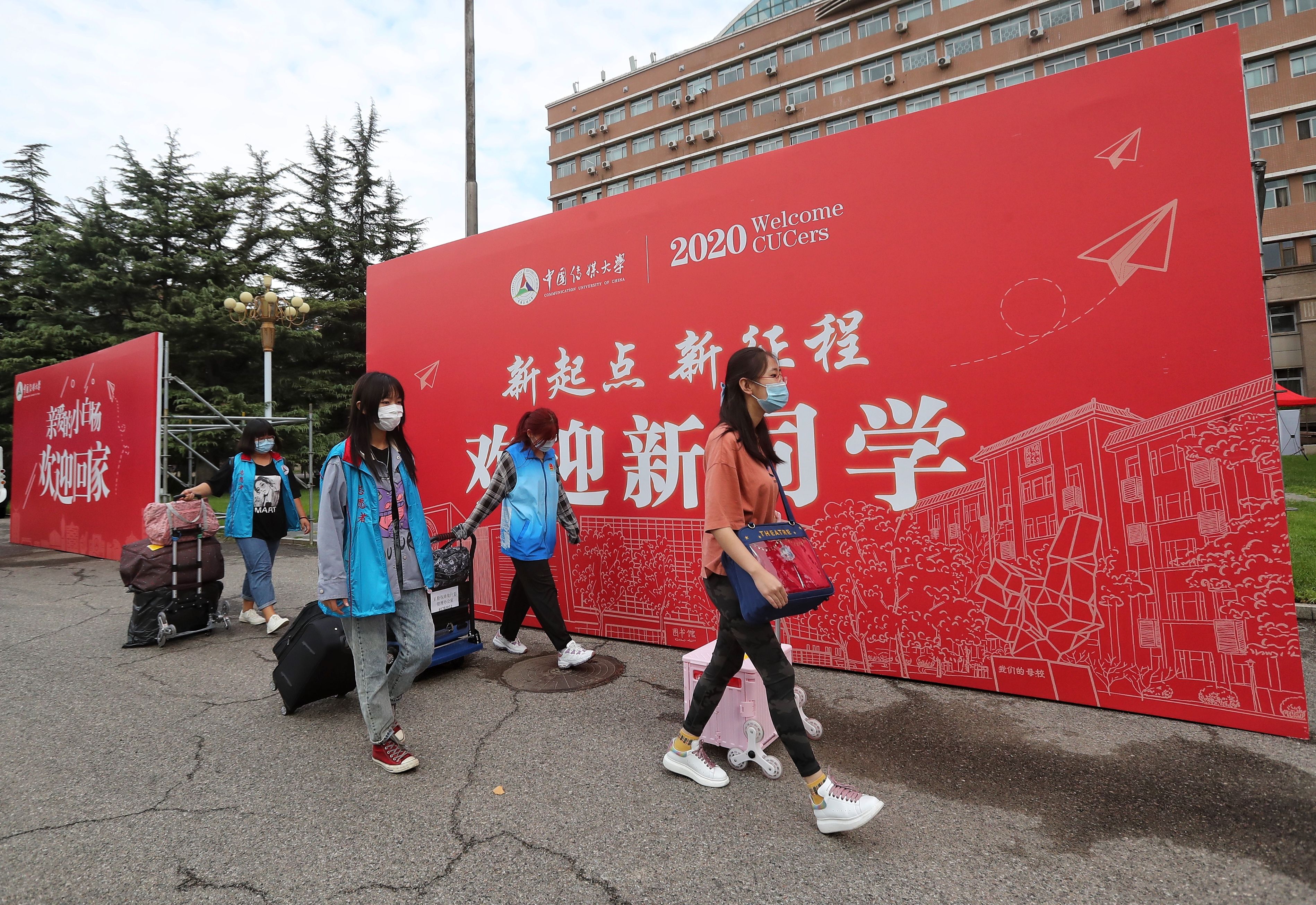 中国传媒大学新生报到的首日,穿着蓝马甲的志愿者用小推车帮助新生