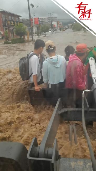接地气的“硬核”救援！铲车变身救援车 在积水中转移一群人