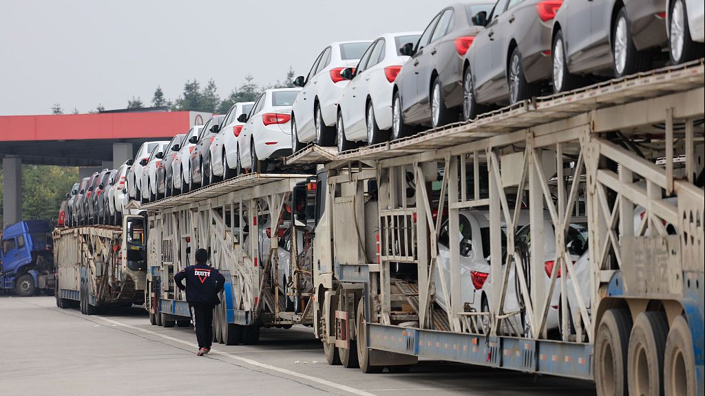 高速服务区,运输车装载着崭新的商品小汽车停靠休息,场景壮观酷似摆长龙
