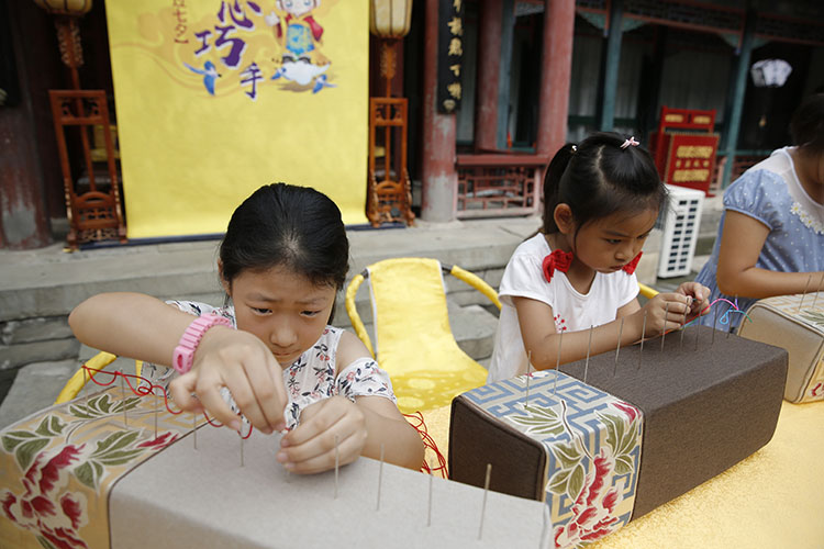 女孩们用五色彩线,穿过依次排列在软枕上的10个针孔.