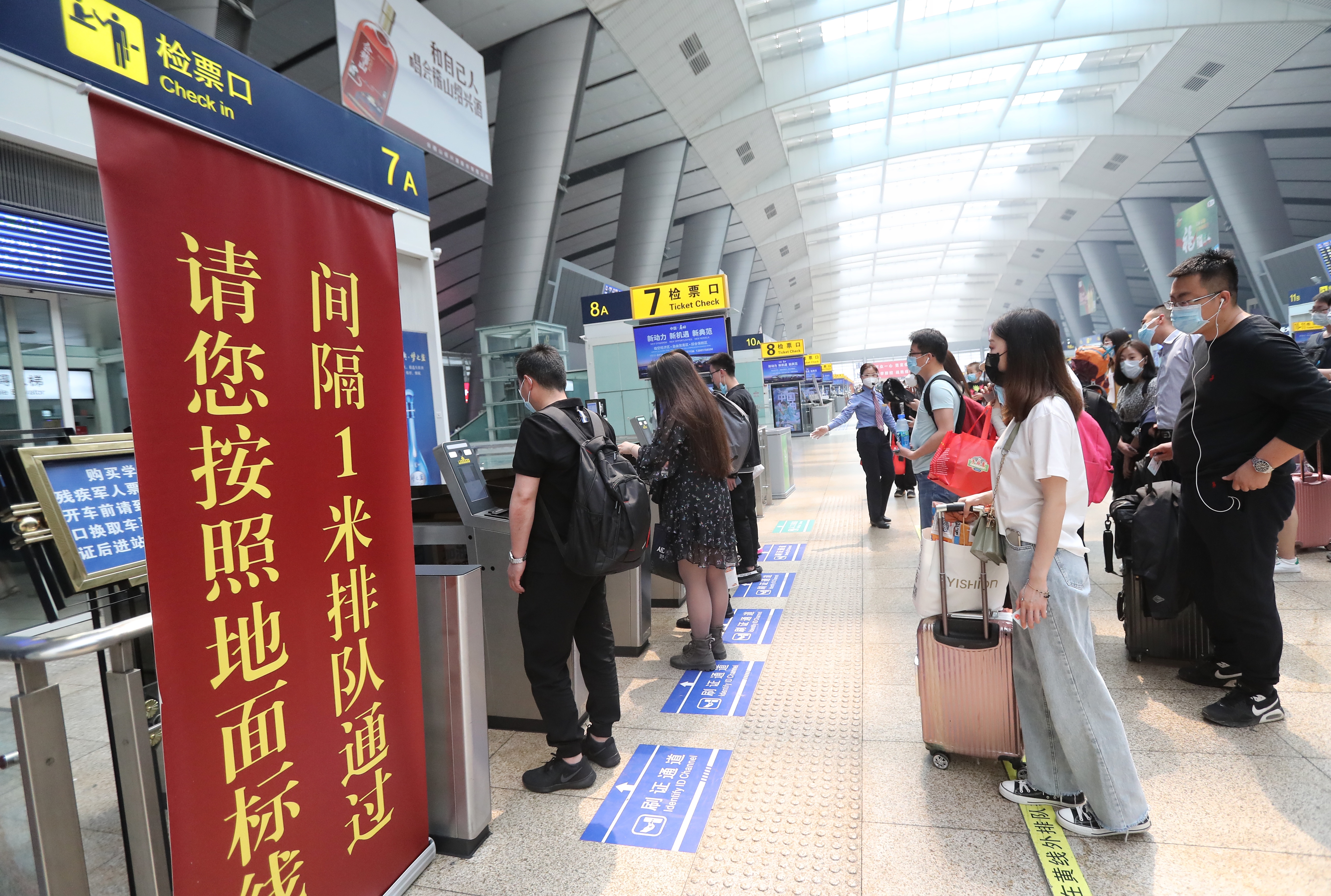 今天上午,在北京南站二楼进站平台,工作人员正在引导检票乘客保持一米
