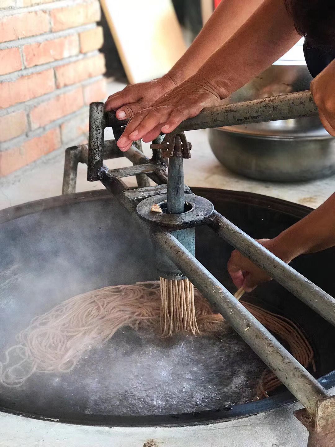 进饸饹床，用力下压手柄，面条从饸饹床底部圆孔中挤出，直接落入沸水。制作饸饹面。密云区金叵罗村供图尽管