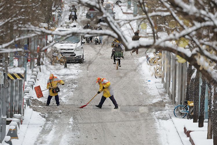 工人体育场北路,环卫工人在马路上清扫积雪